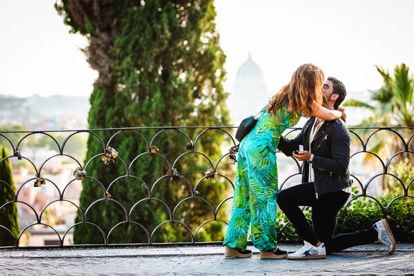 Couple kissing during their surprise wedding proposal shoot on the Terrazza Belvedere in Rome at sunset