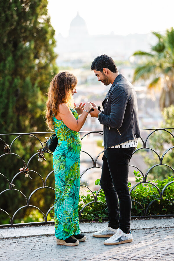 Couple during their wedding proposal in Rome on the Terrazza Belvedere putting the engaegment ring on
