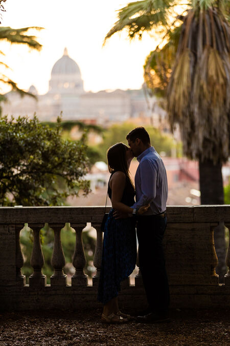Low-key image of newly-engaged couple kissing at the Pincio Gardens with the Vatican in the background