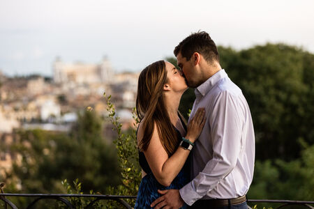 Newly-engaged couple kissing at sunset on the Terrazza Belvedere during their marriage proposal photo session in Rome 