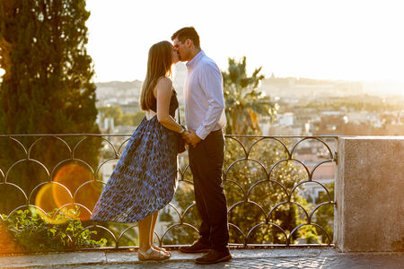 Couple kissing on the Terrazza Belvedere during their surprise proposal photo session at sunset in Rome
