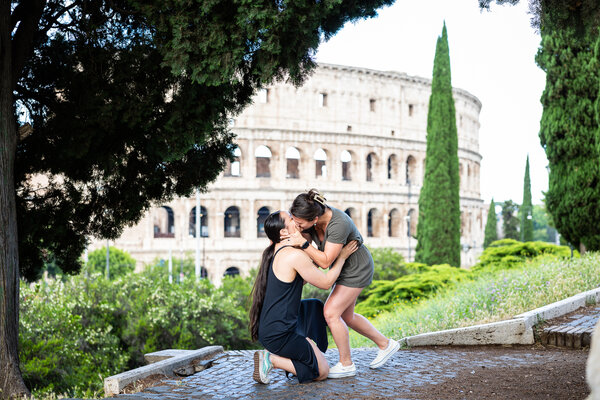Same-sex couple kissing during a surprise wedding proposal on Monte Oppio by the Colosseum in Rome