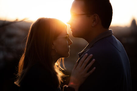 Guy about to kiss his fiancé on her forehead during their sunset proposal photo shoot at the Pincio Gardens in Rome