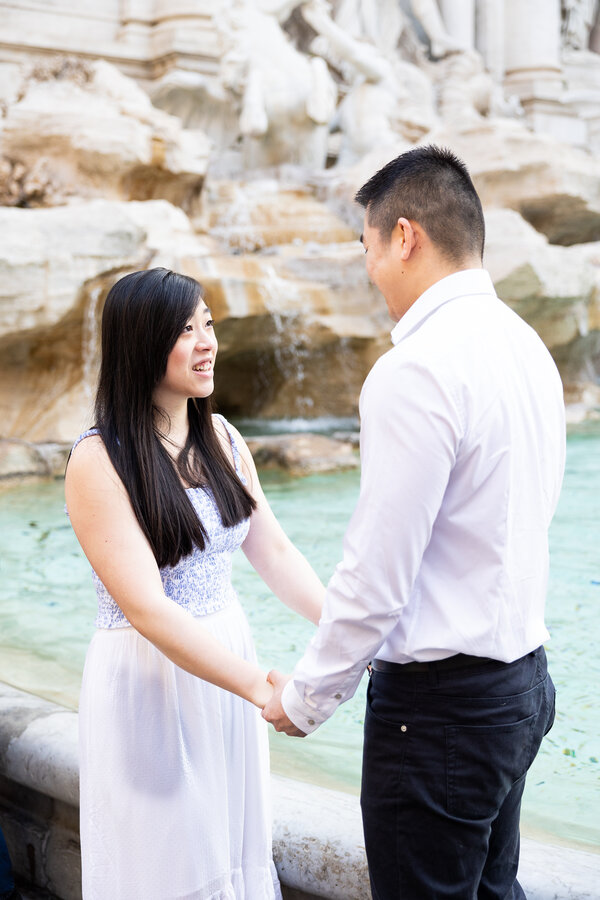 Couple holding hands during their wedding proposal at the Trevi Fountain in Rome