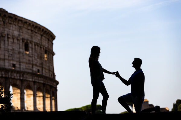 Silhouette of couple proposing with the Colosseum in the background.