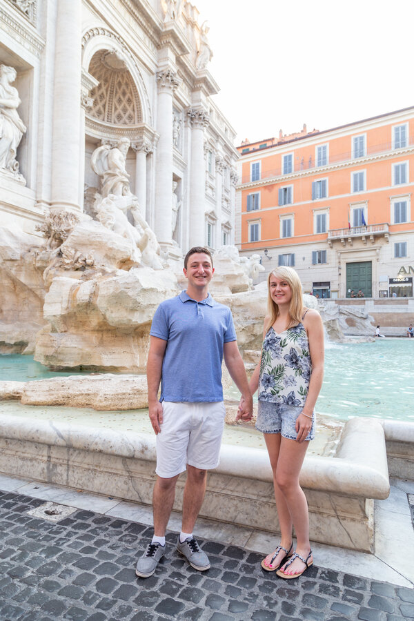 Newly-engaged couple posing at the Trevi Fountain during their Proposal Photo Session in Rome