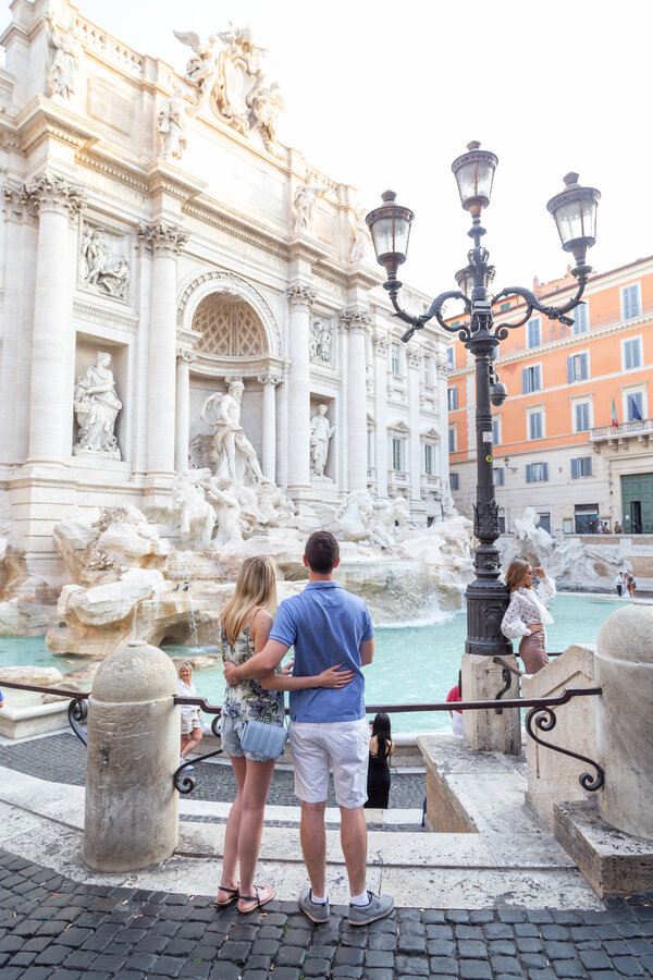 Newly-engaged couple enjoying the majestic beauty of the Trevi Fountain during their engagement photo session in Rome