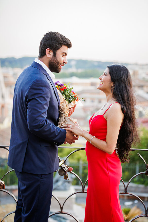 Newly-engaged couple smiling at each other during their surprise proposal photo shoot in Rome