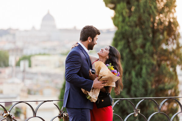 Newly-engaged couple holding and smiling at each other during their surprise proposal photo shoot in Rome