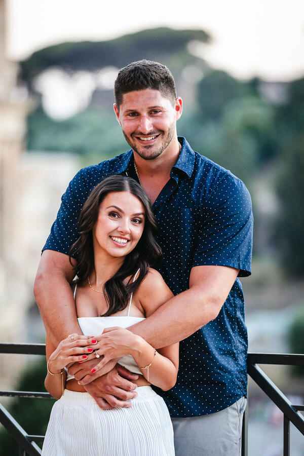 Happy newly-engaged couple smiling for the camera during their surprise propsoal photo session in Rome