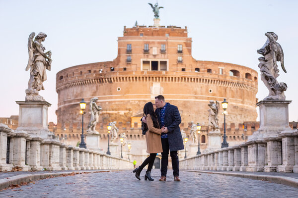 Couple standing on Castel Sant'Angelo Bridge at sunrise