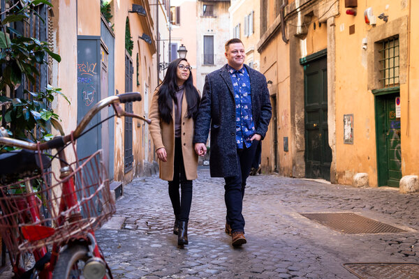Couple walking in a downtown alley in the centre of Rome during their engagement photo session