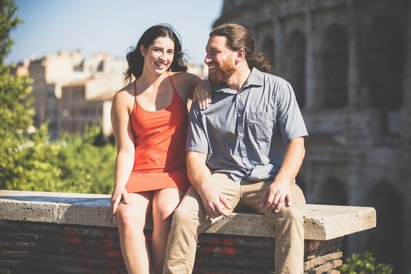 Happy newly-engaged couple sitting with the Colosseum in the background