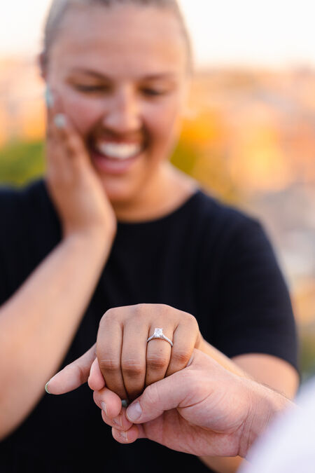 Happy fiancée showing off her beautiful engagement ring during a surprise wedding proposal in Rome