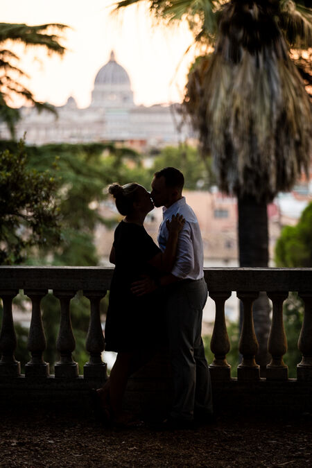 Newly-engaged couple kissing at the Pincio gardens with the Vatican in the background
