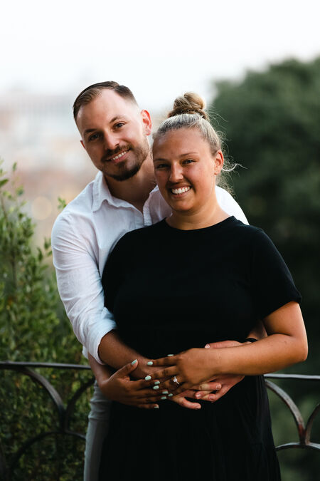 newly-engaged couple smiling for the camera during their surprise proposal photo shoot on the Terrazza Belvedere in Rome at susnet
