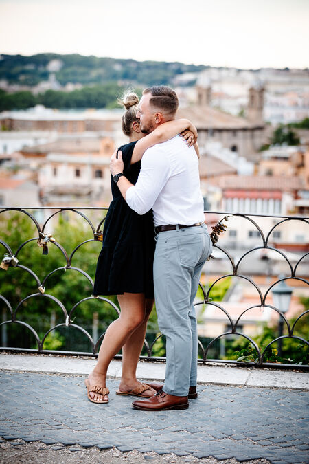 Couple hugging during their surprise proposal photo shoot on the Terrazza Belvedere in Rome
