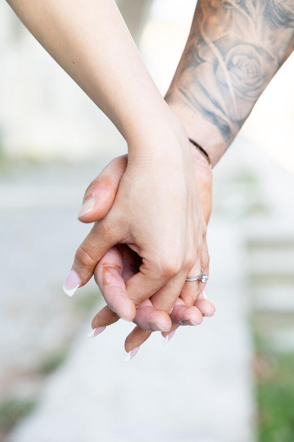 Close-up image of newly-engaged couple holding hands and showing off the engagement ring