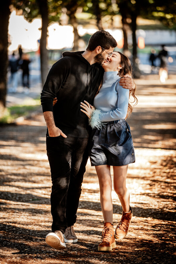 Beautiful newly-engaged couple walking and kissing in Villa Borghese during the surprise wedding proposal photoshoot in Rome