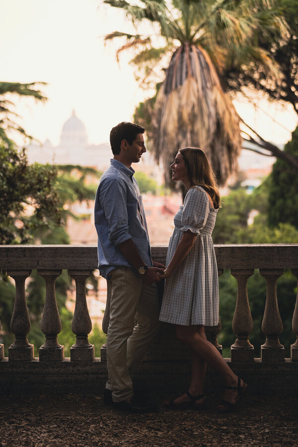 Newly-engaged couple holding hands during their surprise proposal in Rome with the Vatican in the background