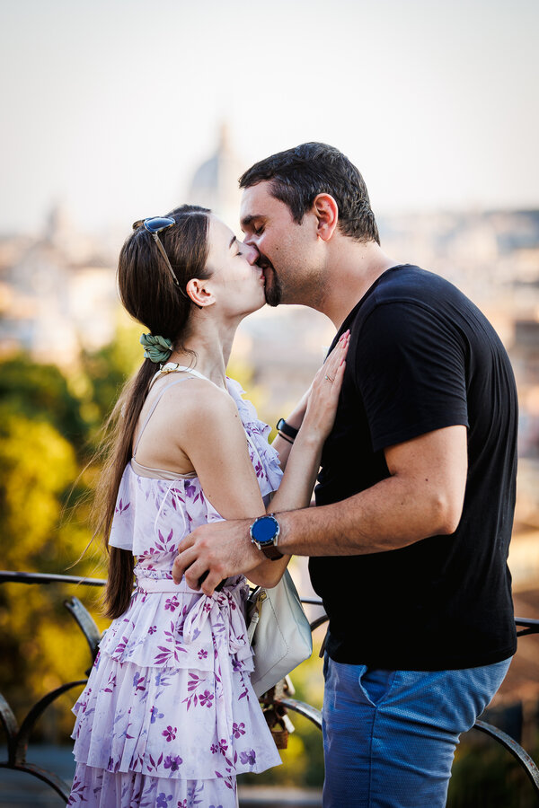 Newly-engaged couple kissing after their surprise proposal at the Pincio Gardens in Rome