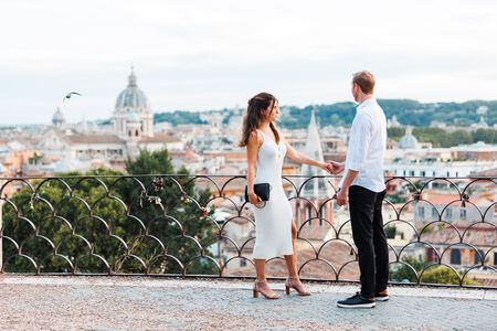 Beautiful couple holding hands on the Terrazza Belvedere during their surprise wedding proposal at sunset in Rome