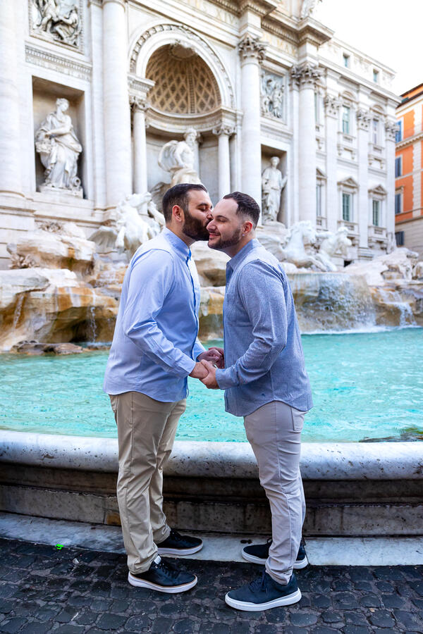 Gay couple kissing each other by the Trevi Fountain moments before their surprise wedding proposal in Rome