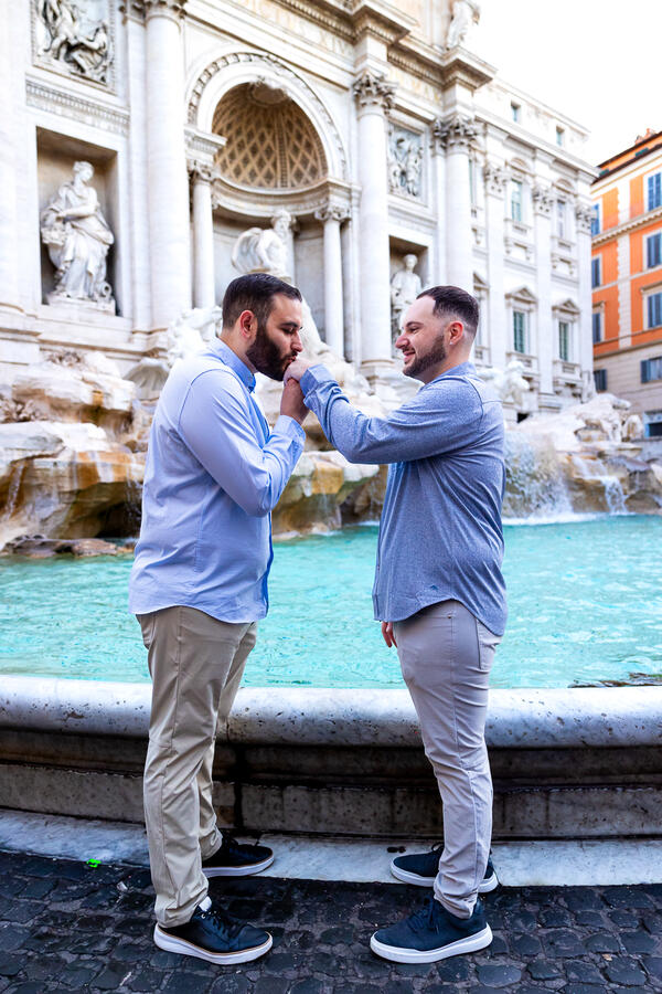 Guy kissing his future fiancée's hands by the Trevi Fountain in Rome