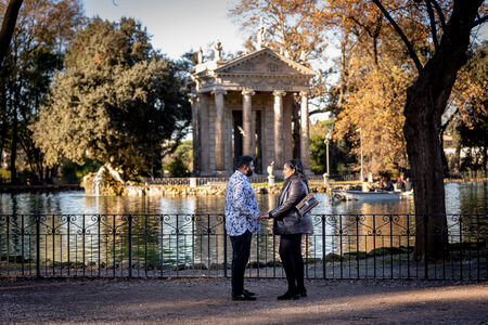 Couple holding hands during their surprise wedding proposal by the pond in Villa Borghese in Rome