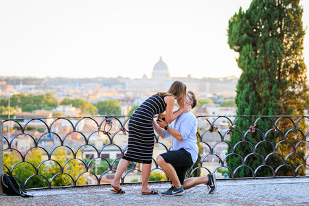Couple kissing during their surprise proposal on the Terrazza Belvedere at sunset in Rome