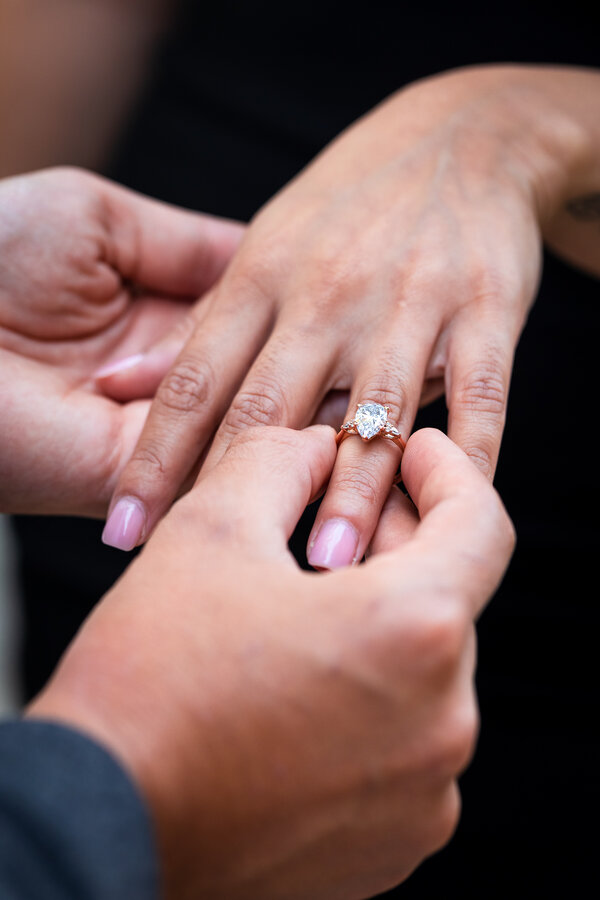 Close-up of the engagaement while being placed on the fiancée's finger