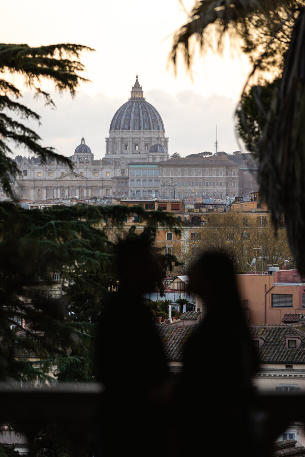 Newly-engaged couple in silhouette with the Vatican in the background at sunset