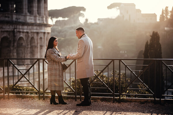 Couple holding hands on the Giardinetto del Monte Oppio at sunset with the Colosseum in the background