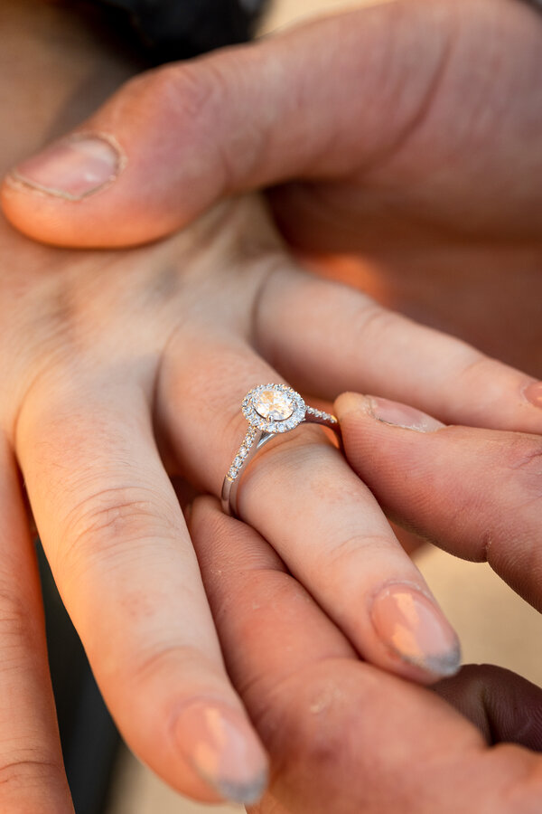 Close-up image of the engagement ring on the fiancèe's finger