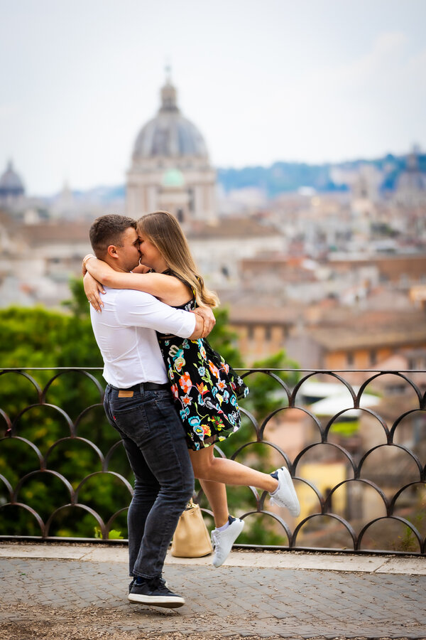 Happy newly-engaged couple in Rome spins in joy on the Terrazza Belvedere