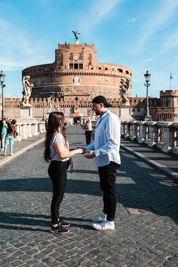 Couple holding hands on Castel Sant'Angelo Bridge, moments before their wedding proposal in Rome