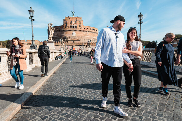 Happy newly-engaged couple walking on Castel Sant'Angelo Bridge