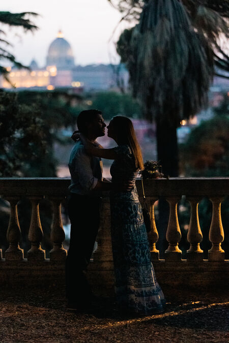 Newly-engaged couple kissing at the Pincio Gardens after sunset with the Vatican in the background