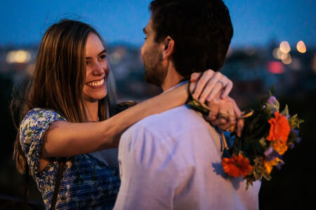 Finacée holding flowers while hugging her future husband-to-be during their surprise proposal photo shoot on the Terrazza Belvedere