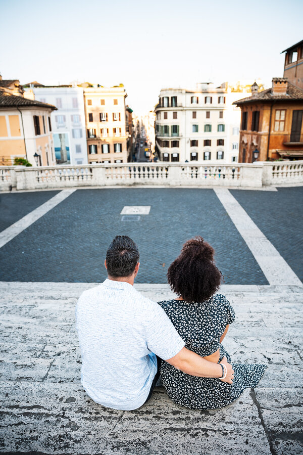 Couple sitting on the Spanish Steps in Rome during their engagement photo session in Rome