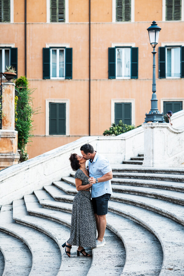 Newly-engaged couple kissing on the Spanish Steps during their engagement photo session in Rome