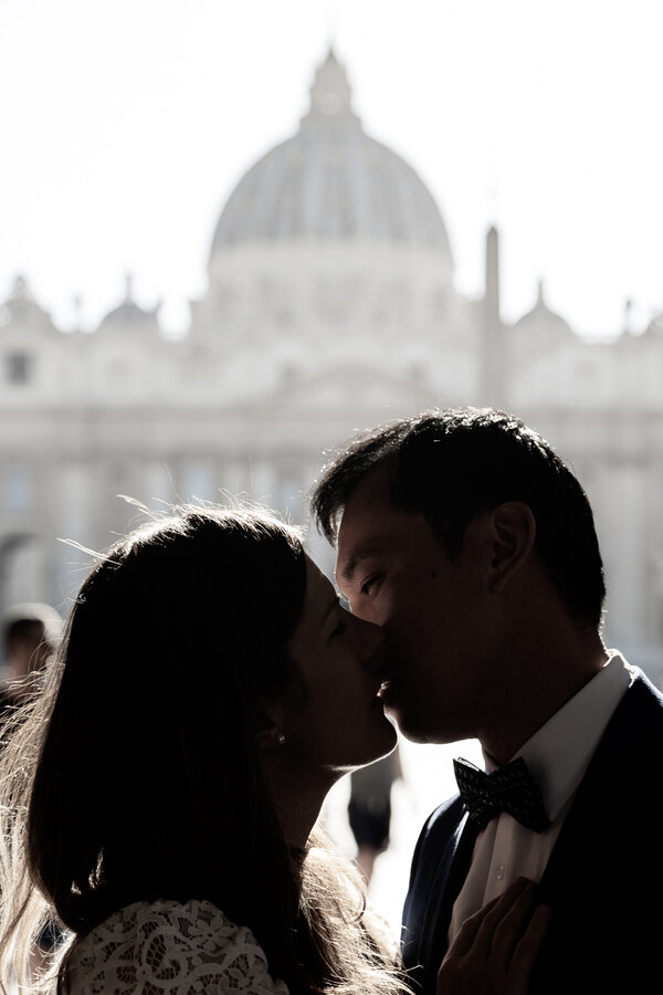 Sposi Novelli kissing in silhouette with the Vatican in the background