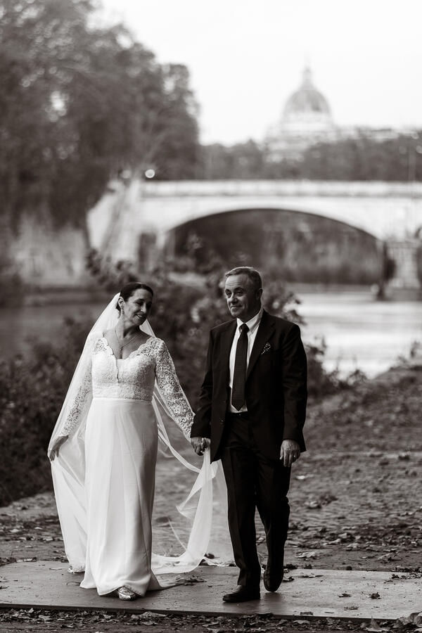 Sposi Novelli couple strolling hand in hand along Tiber riverbank in Rome