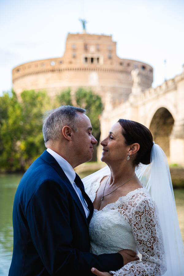 Romantic shot of Sposi Novelli Couple about to kiss with Castel Sant'Angelo in the background