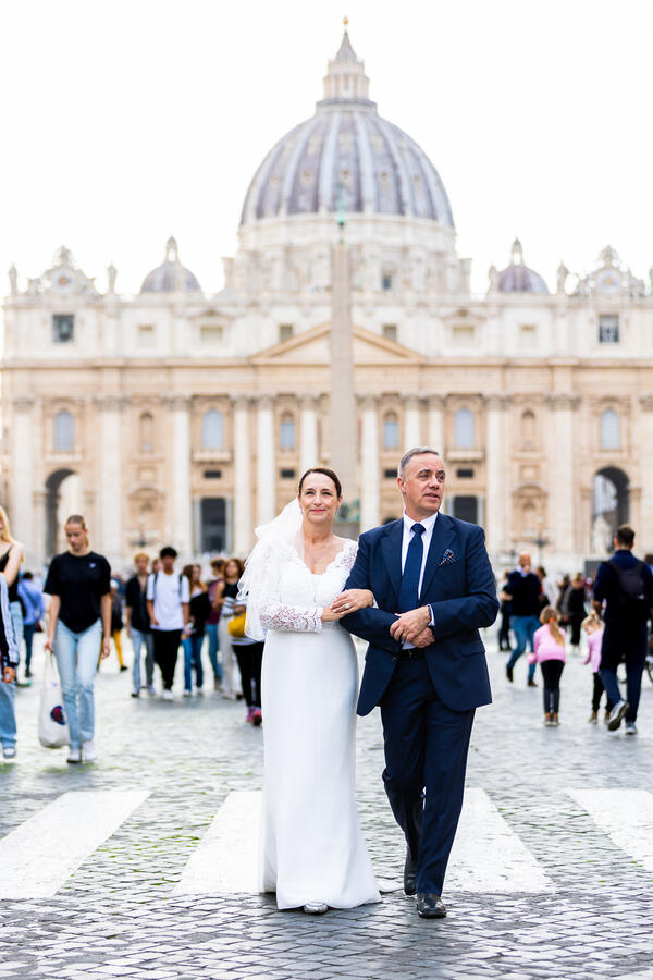 Elegant newly-wed Sposi Novelli walking down Via della Conciliazione with the Vatican in the background