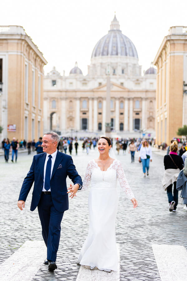 Happy newly-web couple walking down Via della Conciliazione during their Sposi Novelli photoshoot in Rome