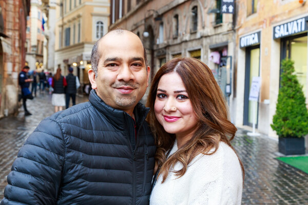Husband and wife smiling at the camera on their vacation photo session in Rome