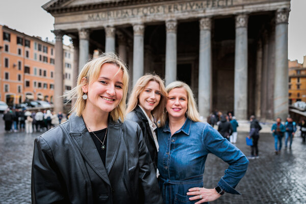 Older daughter posing for the camera with mother and sister in the background at the Pantheon