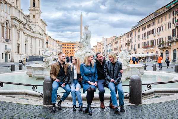 Family all sitting together and laughing in Piazza Navona during their family photoshoot in Rome