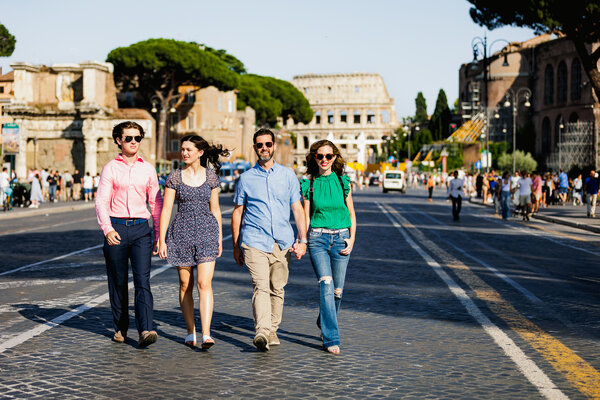 Family of 4 walking down Via dei Fori Imperiali with the Colosseum in the background